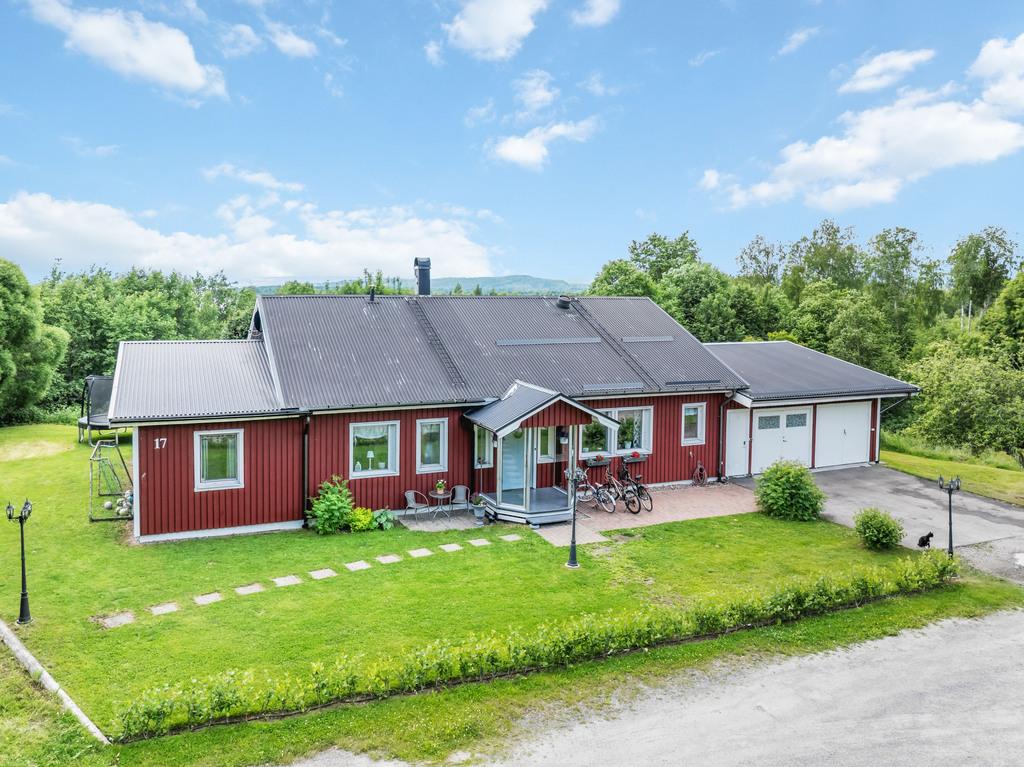 Representativ entrésida med välskött trädgård och generösa parkeringsytor.